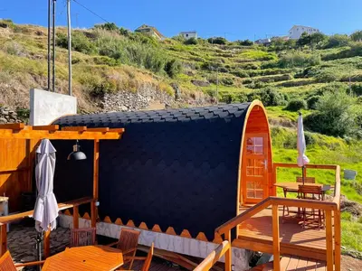 a igloo house with tables and chairs and a hill at The tiny black bird in Fajã da Ovelha