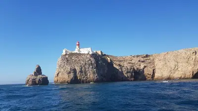 a lighthouse on top of a rock in the water at Laurus - Charming House in Raposeira