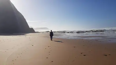 a man walking on the beach near the ocean at Laurus - Charming House in Raposeira