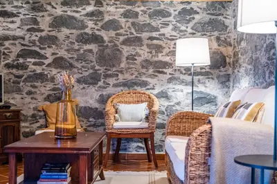a living room with a stone wall at Rainbow Cottage by Homie in Ponta do Pargo