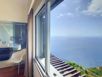 a room with a balcony with a view of the ocean at Villa Miradoura by LovelyStay in Arco da Calheta
