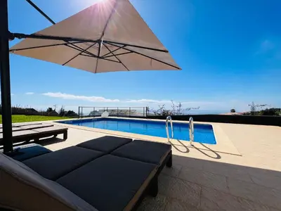 a patio with a couch and an umbrella next to a pool at Villa Carpe Diem by Your Madeira Rentals in Estreito da Calheta
