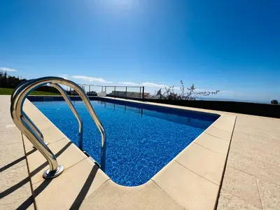 a swimming pool with a metal rail next to the water at Villa Carpe Diem by Your Madeira Rentals in Estreito da Calheta