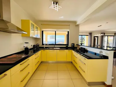 a kitchen with yellow cabinets and black counter tops at Villa Carpe Diem by Your Madeira Rentals in Estreito da Calheta
