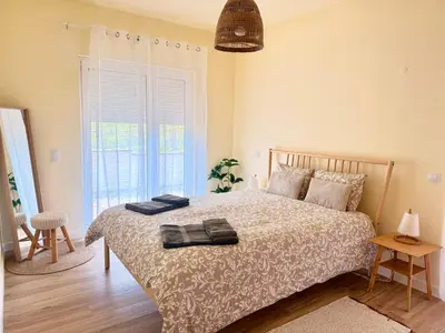 a bedroom with a large bed with two windows at Casa Kiko in Burgau