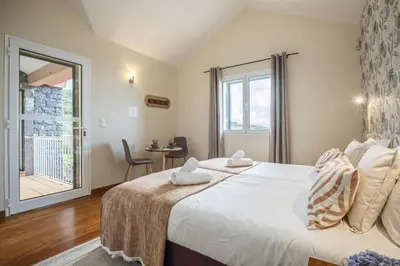 a bedroom with a large bed and a balcony at Casas do Salao by Homie in Porto Moniz