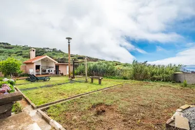a yard with a house with a hill in the background at Casas do Salao by Homie in Porto Moniz