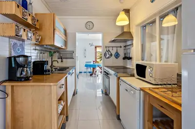 a large kitchen with white cabinets and a sink at Casa da Praia in Vila Baleira