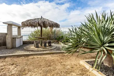 a patio with a table and an umbrella at Casa da Praia in Vila Baleira