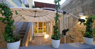 an umbrella on a table with two potted plants at Little Townsuite Funchal in Funchal
