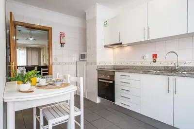 a kitchen with white cabinets and a table and chairs at My Place in Funchal by Homie in Funchal