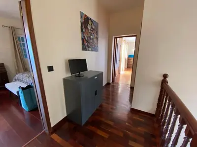 a living room with a television on a dresser and a staircase at Villa Paraiso - Traumgarten, Meerblick, Wandern und Golf in Funchal