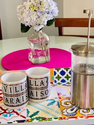 a table with two cups and a vase with flowers at Villa Paraiso - Traumgarten, Meerblick, Wandern und Golf in Funchal