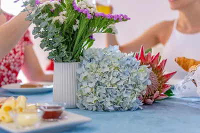a vase of flowers on a table with a plate of food at Casa de Sao Tiago 2 in Funchal