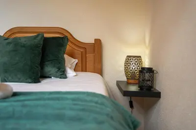 a bed with green pillows and a side table with a lamp at Vigário House in Câmara de Lobos