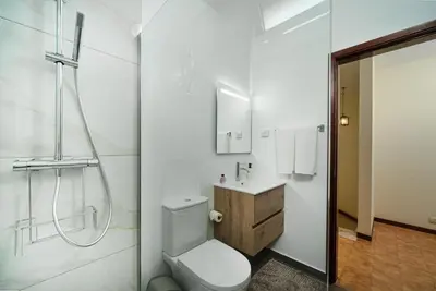 a white bathroom with a toilet and a shower at Vigário House in Câmara de Lobos