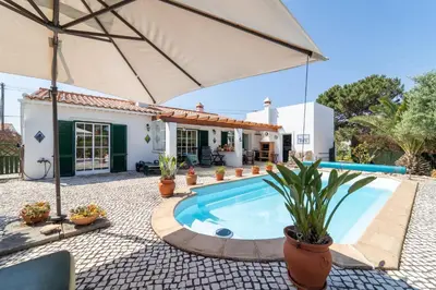 a villa with a swimming pool and an umbrella at Bliss Villa in Aljezur