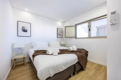 a bedroom with a bed with white sheets and a window at Filha do Pisco in Burgau