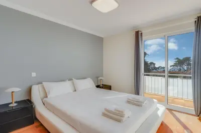 a bedroom with a white bed and a large window at Boeiro I in Caniço