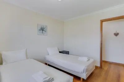 a white room with two beds and a mirror at Boeiro I in Caniço