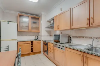 a kitchen with wooden cabinets and a sink and a refrigerator at Boeiro I in Caniço