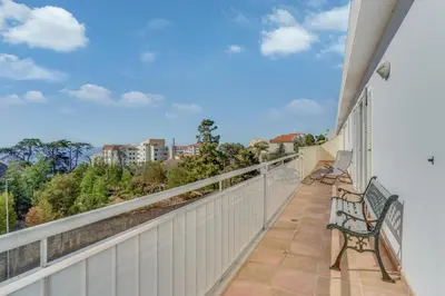 a balcony with a bench and a view of the city at Boeiro I in Caniço