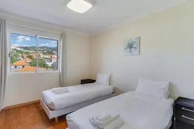 two beds in a room with a window at Boeiro I in Caniço