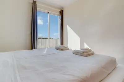 a white bedroom with a large white bed with a window at Boeiro I in Caniço