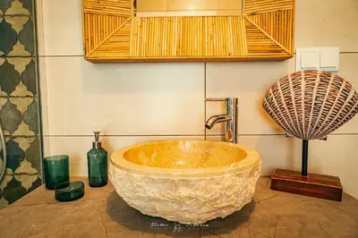 a bathroom with a large stone sink and bottles at Wayra Lodge [Samay] A different sunset every day in Raposeira