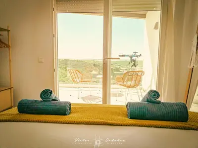 two pillows sitting on a bench in front of a window at Wayra Lodge [Samay] A different sunset every day in Raposeira