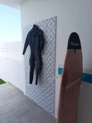 a person in a wetsuit hanging on a wall at Wayra Lodge [Samay] A different sunset every day in Raposeira
