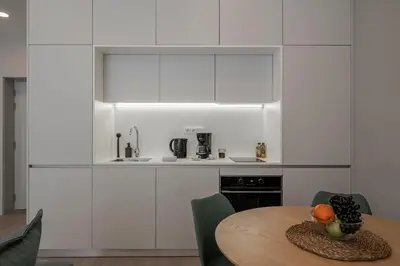 a kitchen with white cabinets and a wooden table at Cine Park Residences by An Island Apart in Funchal