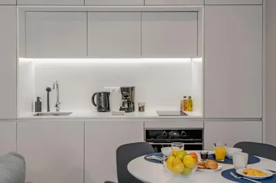 a white kitchen with a table with fruit on it at Cine Park Residences by An Island Apart in Funchal