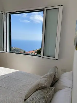 a white bedroom with a bed and two pictures on the wall at Country house in Arco da Calheta
