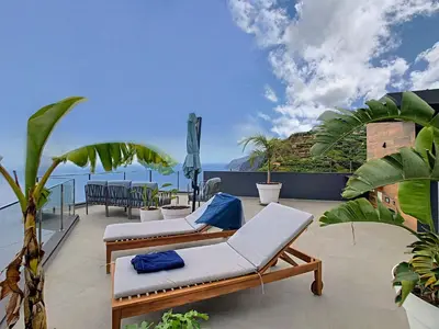 a balcony with two lounge chairs and the ocean at Villa Omar by LovelyStay in Canhas