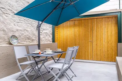 a table with chairs and an umbrella on a patio at Casa do Batente - By WeHost in Funchal