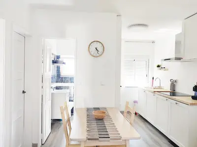 a white kitchen with a table and a clock on the wall at Caroline's in Vila do Bispo
