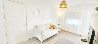 a white living room with a white chair and a door at Caroline's in Vila do Bispo