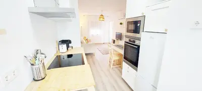 a kitchen with white appliances and a wooden table at Caroline's in Vila do Bispo