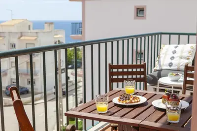 a wooden table with a plate of food and two glasses of orange juice at B73 - Luz Sun Holiday Apartment in Lagos