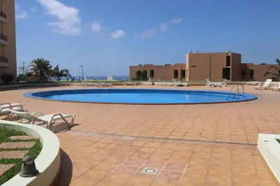 a large swimming pool in a courtyard with chairs at Garajau Terrace Orchids in Caniço