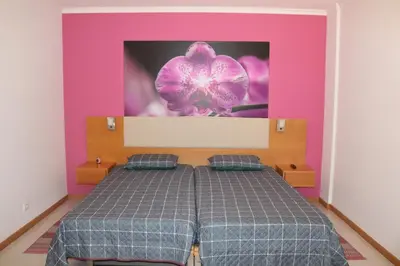 a bedroom with a bed with a purple and pink wall at Garajau Terrace Orchids in Caniço
