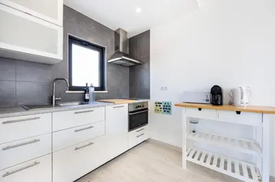 a kitchen with white cabinets and a sink and a window at Villa Drop in in Sagres