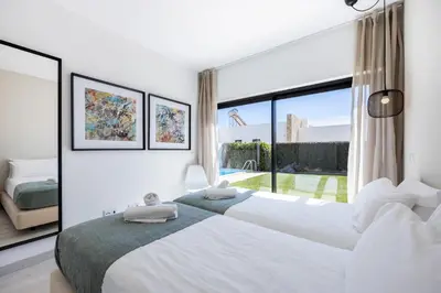 a white bedroom with two beds and a large window at Villa Drop in in Sagres