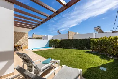 a patio with chairs and a lawn in a backyard at Villa Drop in in Sagres