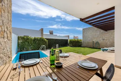 a wooden table with plates and wine bottles on a patio at Villa Drop in in Sagres