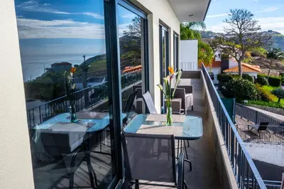 a balcony with two tables and a view of the ocean at Apartamento Domingos in Arco da Calheta