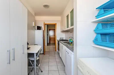 a kitchen with white cabinets and blue shelves at Sonho Dourado Apartamento de praia in Porto Santo