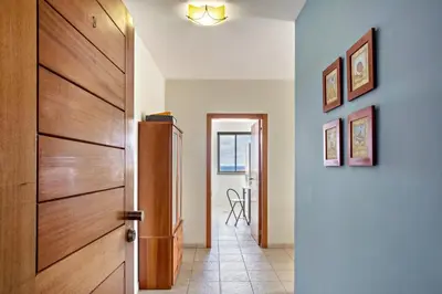 a hallway with a wooden door and a table at Sonho Dourado Apartamento de praia in Porto Santo
