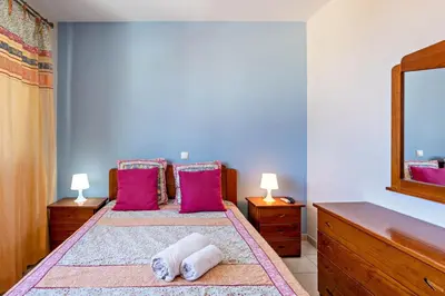 a bedroom with two beds with pink pillows and a mirror at Sonho Dourado Apartamento de praia in Porto Santo